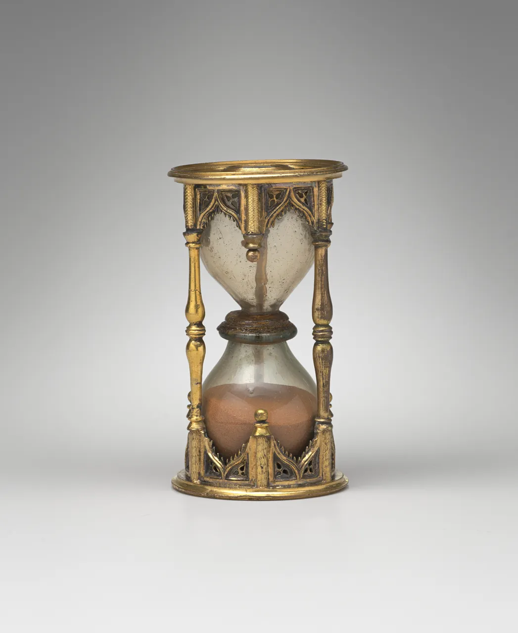 A half-hour sandglass in a gilded frame of slender columns, the sand settled in the lower bulb.