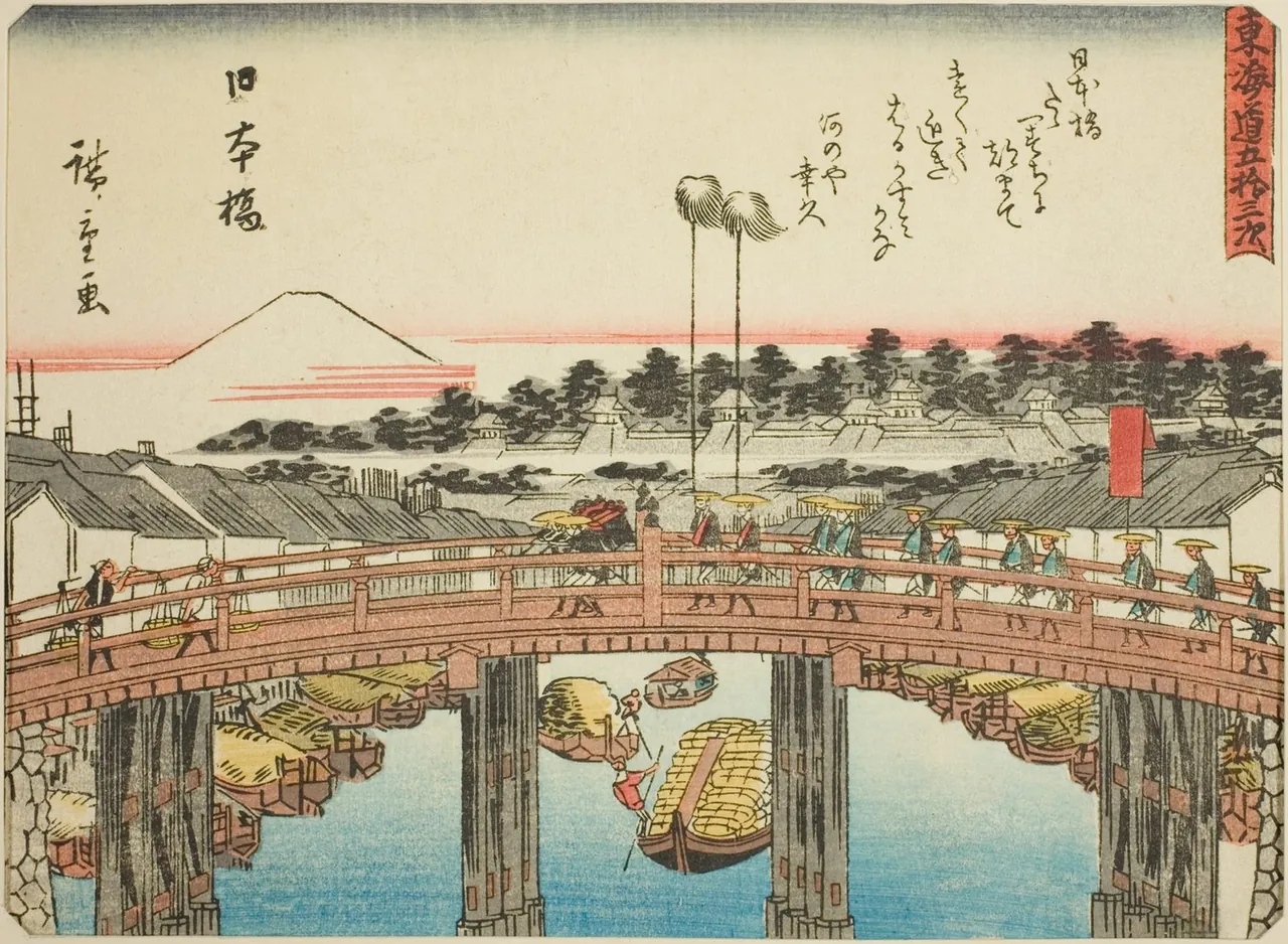 The arched wooden Nihonbashi bridge in Edo crowded with people, boats on the river below and Mount Fuji white in the distance.