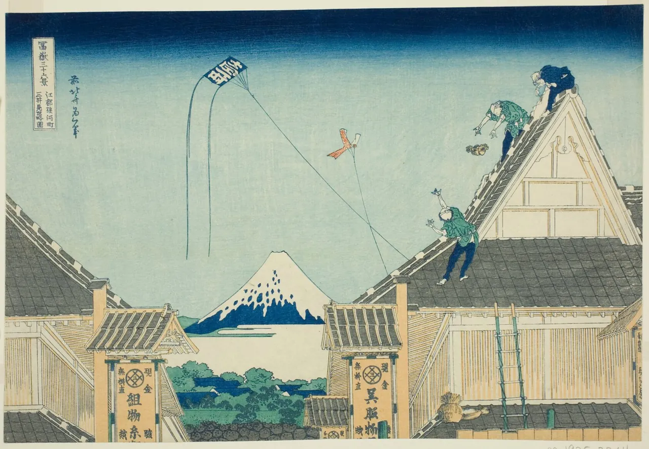 Workmen repair the tiled roof of the large Mitsui dry-goods shop while kites fly overhead and Mount Fuji rises between the roofs.
