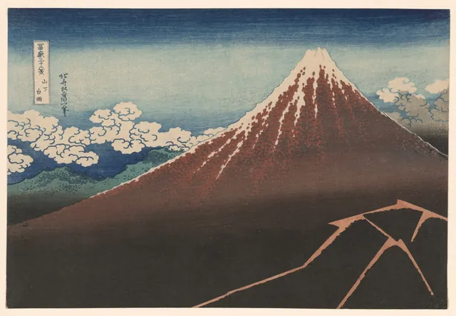 Mount Fuji rises dark red against an indigo sky while lightning flashes in the storm on its lower slopes.