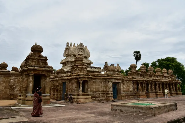 A photograph of the sandstone Kailasanatha temple at Kanchipuram, its central tower and smaller shrines enclosed by a wall lined with small cells.