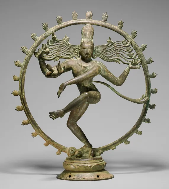 A bronze statue of Shiva dancing on a small figure, four arms spread, inside a ring of flames.