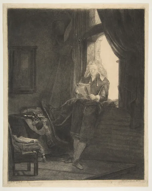 A young man in a long coat stands by a bright window, leaning against the sill and absorbed in reading a book, the room around him in deep shadow.