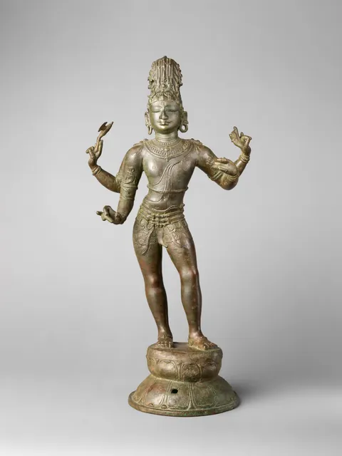 A bronze of Shiva standing in a slight sway on a lotus pedestal with four arms, the lower hands posed as if holding a bow and arrow that are now missing.
